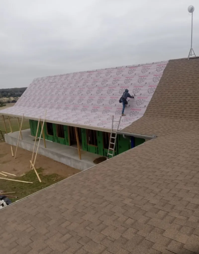 Worker preparing underlayment for a metal roof installation in Senatobia
